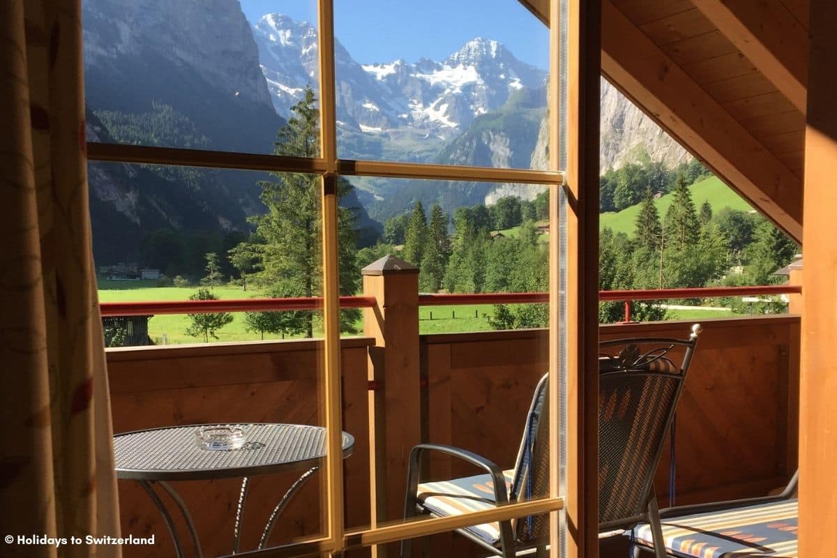 Looking out the window of a Swiss chalet towards snow capped mountains.