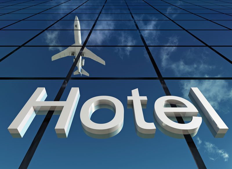 Reflection of aeroplane flying over a building with hotel sign