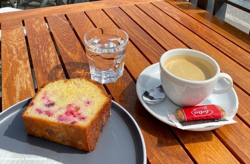 A slice of cake, a glass of water and a cup of coffee on a table