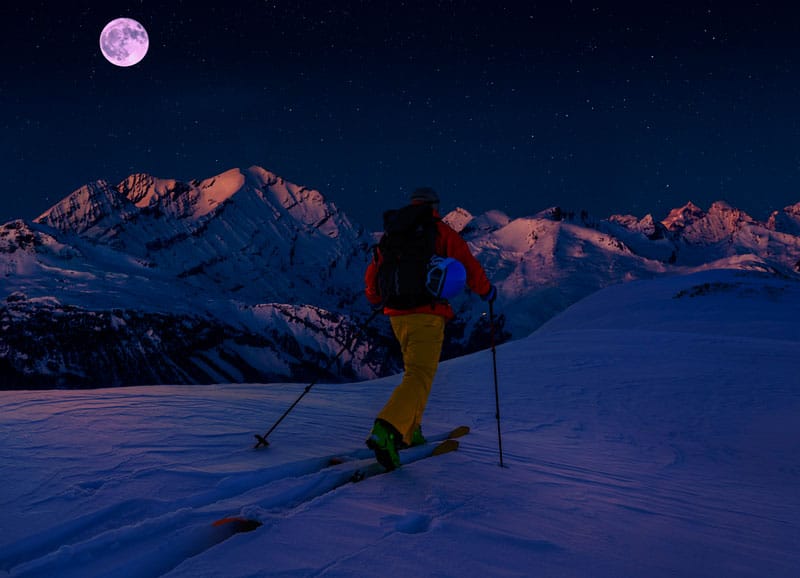 Man cross country skiing at night at Crans Montana in Switzerland