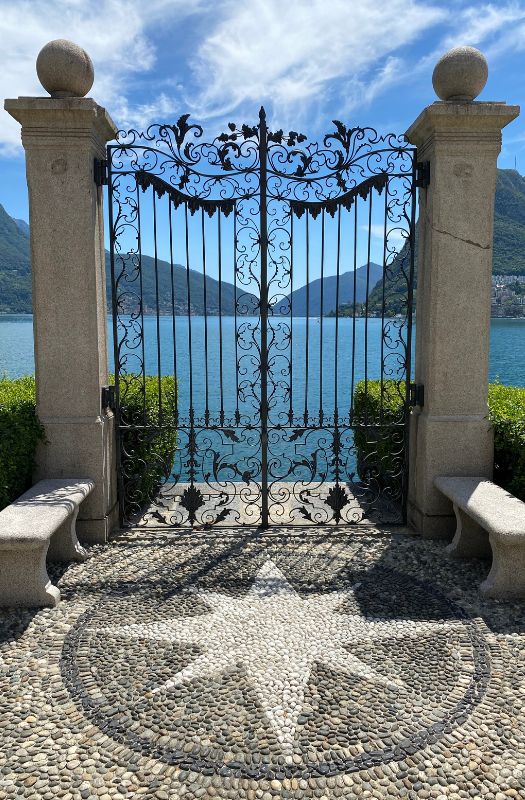 View of Lake Lugano through wrought iron gates at Parco Ciani in Lugano, Switzerland