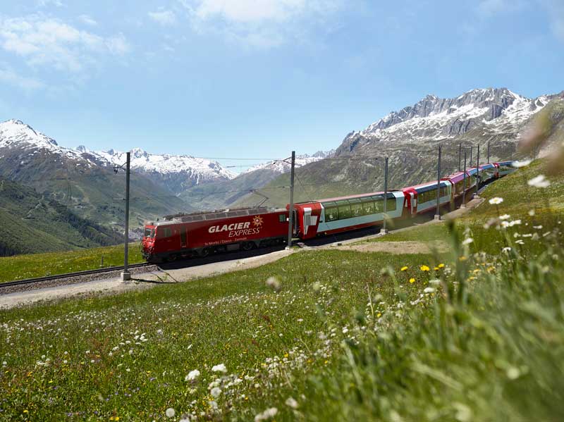 Glacier Express passes a backdrop of snow covered peaks