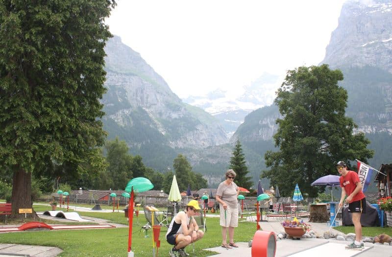 A woman and two teen boys play mini golf at Grindelwald in Switzerland