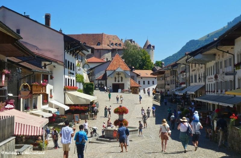 Tourists stroll around the village centre in Gruyeres, Switzerland.