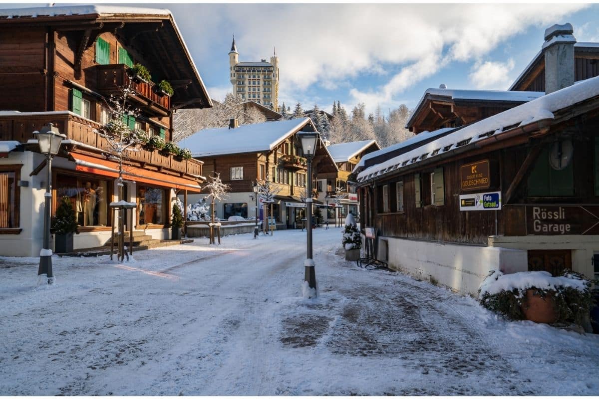 Wooden chalets in the Swiss town of Gstaad during winter with the Gstaad Palace Hotel overlooking the town