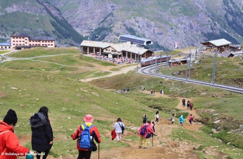 Hikers descend the trail from Riffelsee to Riffelberg on Gornergrat.  The Gornergratbahn waits at the station.