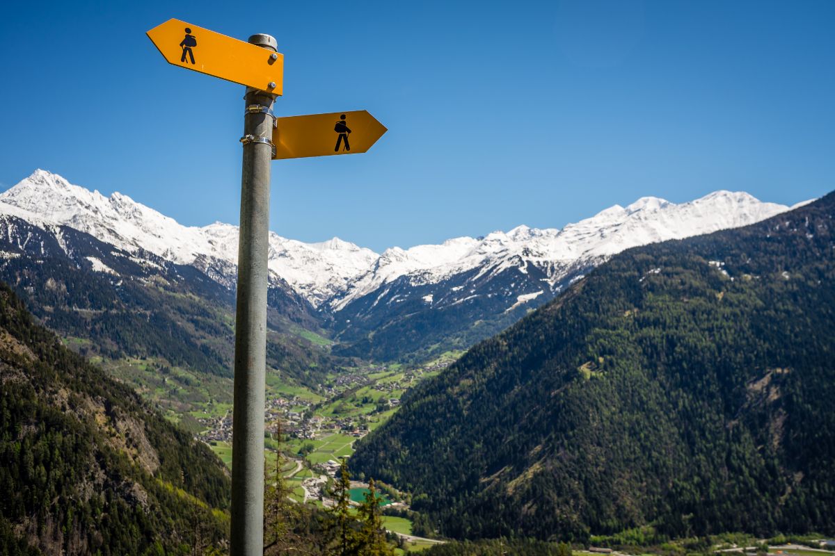 Hiking trail signpost with view to snow capped mountains.