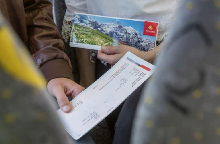 Two people holding Swiss train passes in their hands