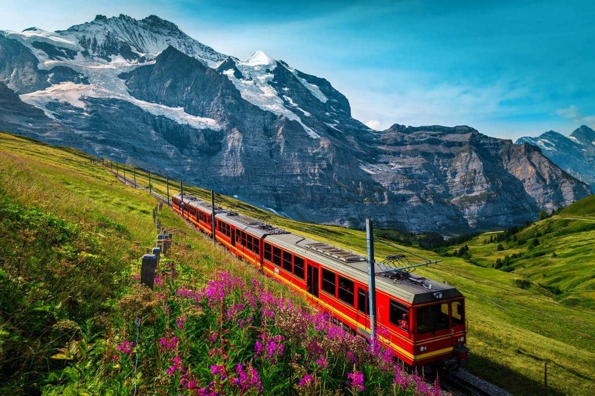 Red Swiss train in front of snow capped mountain