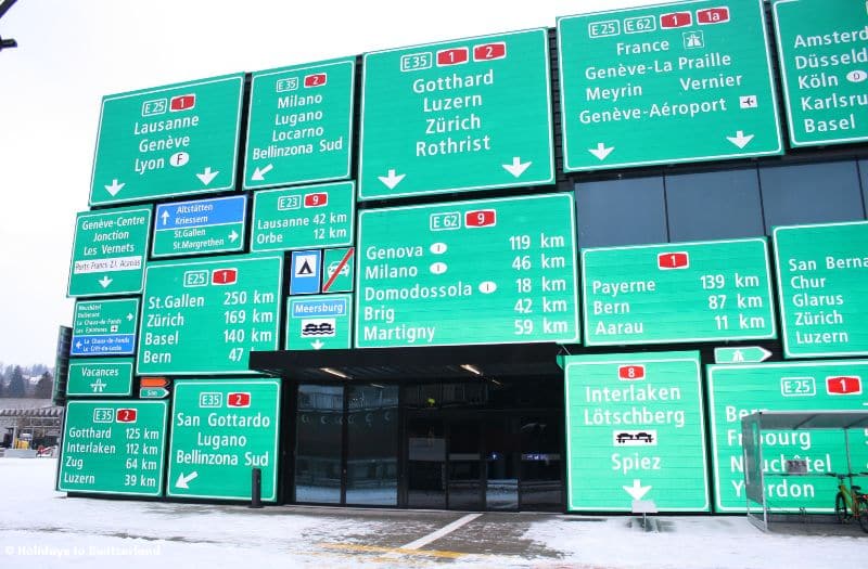 A display of road signs adorns the outside of a building at the Swiss Museum of Transport.