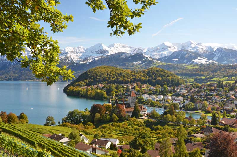 Spiez Castle Switzerland with Lake Thun and Bernese Alps in the distance.