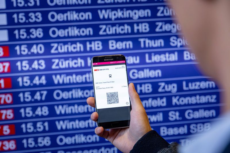 Person holding mobile phone with digital display of Swiss Travel Pass.