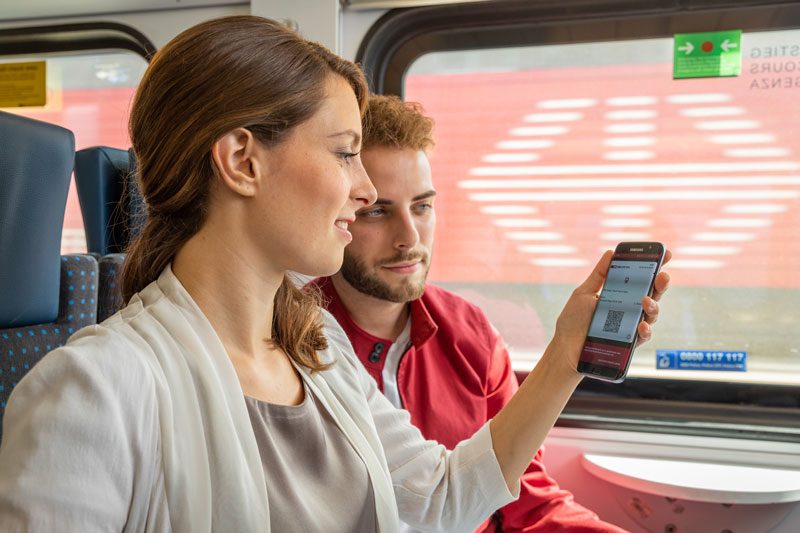 Two passengers on a train looking at their digital ticket on a mobile phone