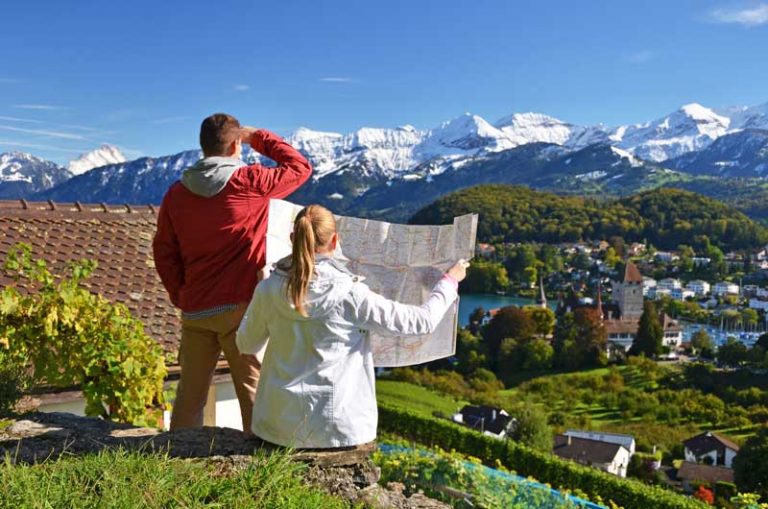 Man and woman overlooking Swiss Alps with a map in hand.