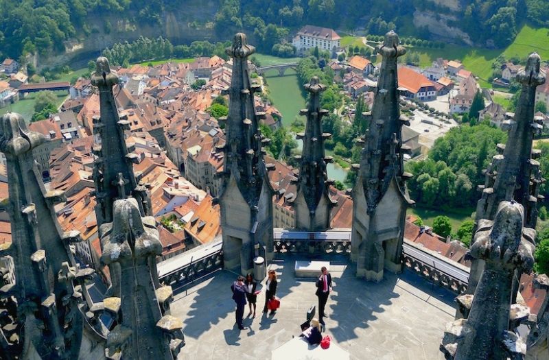 Aerial view of people standing on the rooftop of Fribourg Cathedral with views over the river and Old Town.