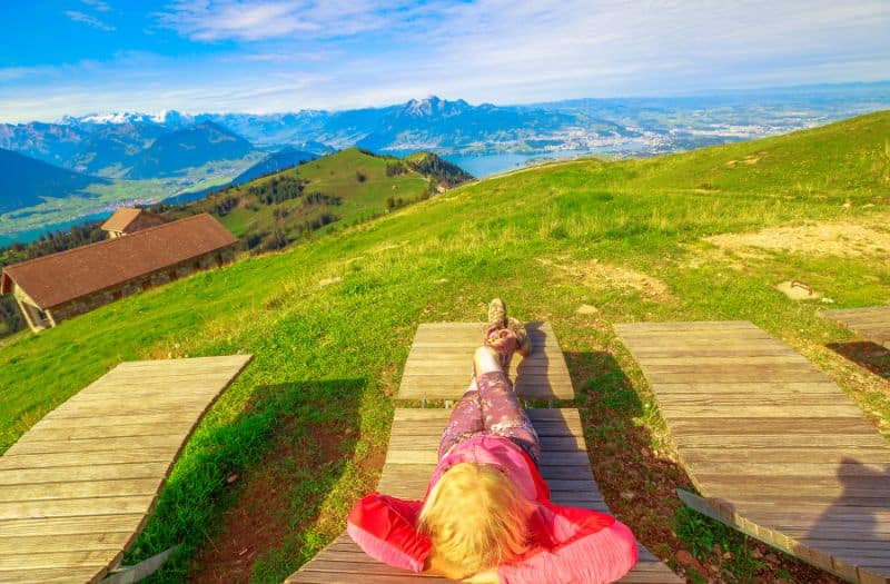 Woman relaxing on a sun bed with scenic views. Mt Rigi is the ideal destination for short breaks and weekend trips from Zurich.