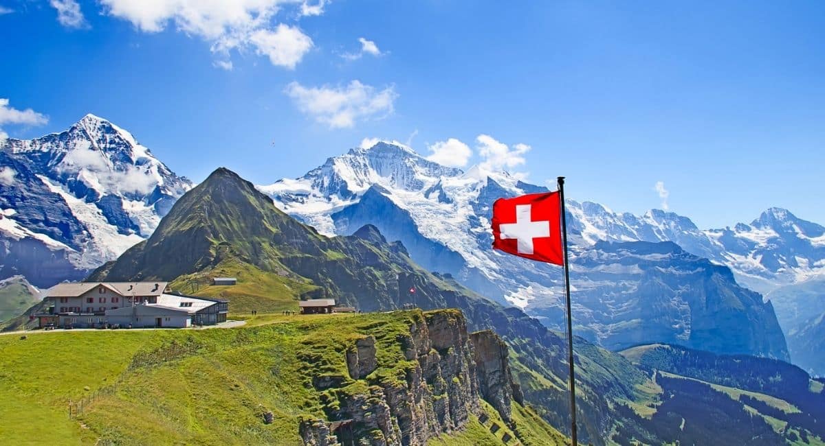 View of Eiger Monch and Jungfrau with Swiss flag in the foreground at Mannlichen.