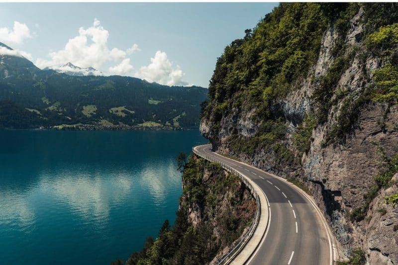 A road winds beside Lake Thun in Switzerland