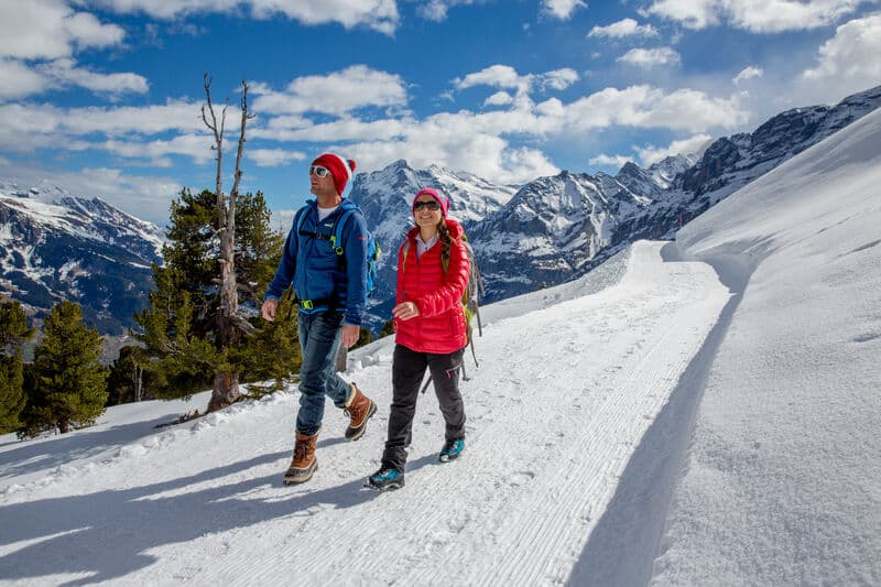 Two hikers walking on the snow in Grindelwald.